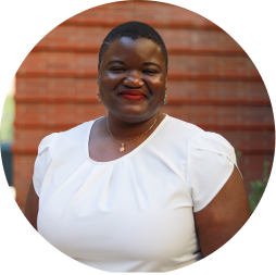 Dr. Tierra S. Bills smiling and standing in front of a red brick wall