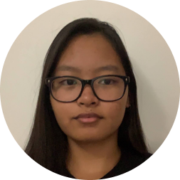 Headshot of a woman with long dark hair and glasses against a neutral beige background.