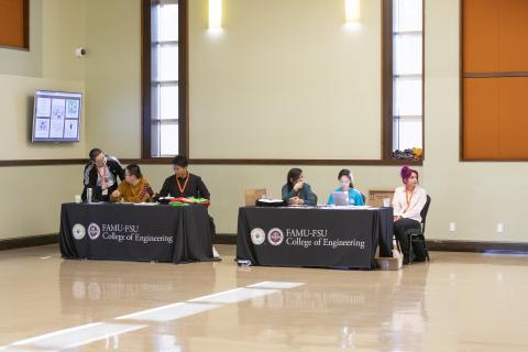Panel discussion at FAMU-FSU College of Engineering with six participants seated at two tables in a large hall.
