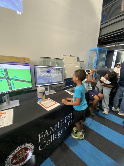 Students interact with computer displays at a Florida A&M University College of Engineering research station, viewing traffic simulation software and virtual reality equipment.